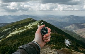 Compass held in hand, overlooking mountain ranges