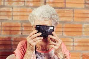 An older lady taking a photo with a vintage camera
