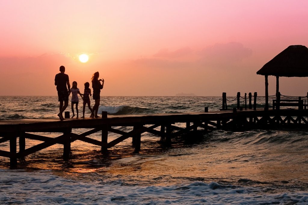 A family of four standing on a dock at sunset