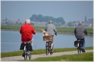 Three elderly people riding bikes along the lake
