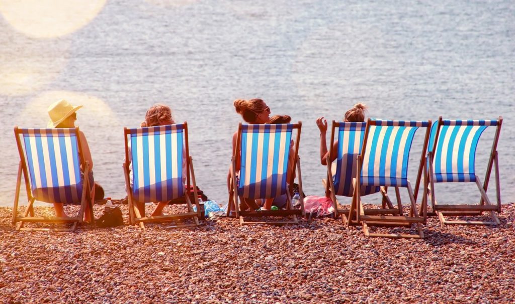 Four people sitting on the beach looking at the sea