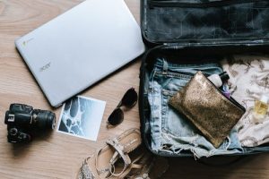 Laptop, sunglasses, clothes and shoes in suitcase
