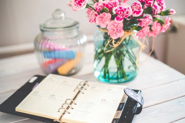 A planner and pink flowers on the table.