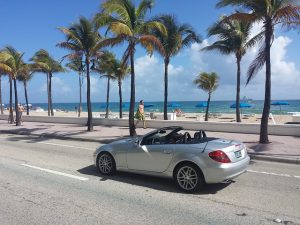 Silver car driving through Miami beach.