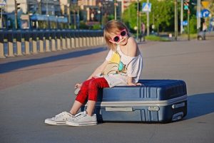 Kid sitting on a suitcase on the street
