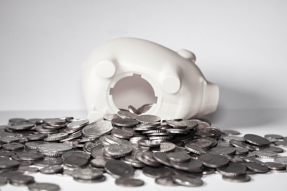 A white piggy bank with coins spilling out of it - finances are key to any coast-to-coast relocation checklist