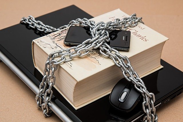 Laptop, book and phone in chains.