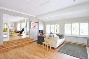protect hardwood floor when moving bulky items by removing everything of the floor. A living room with a rug, sofa and a chair