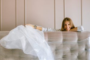 a woman standing behind the couch holding a white protective material