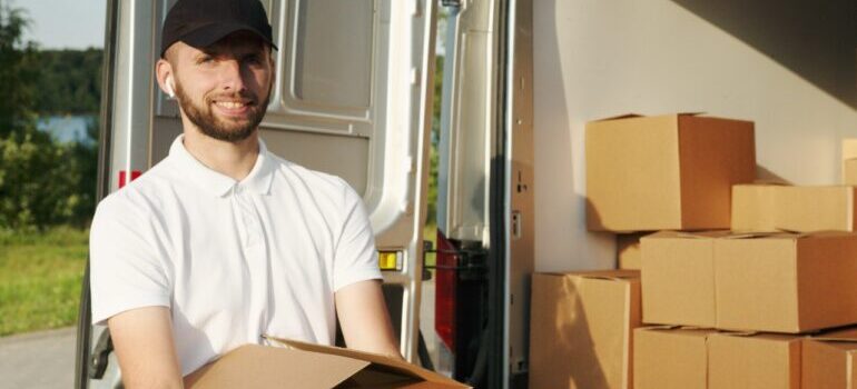 A mover smiling and carrying boxes