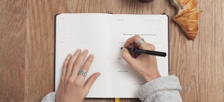 Woman writing in a planner to prepare for moving from Montana to California