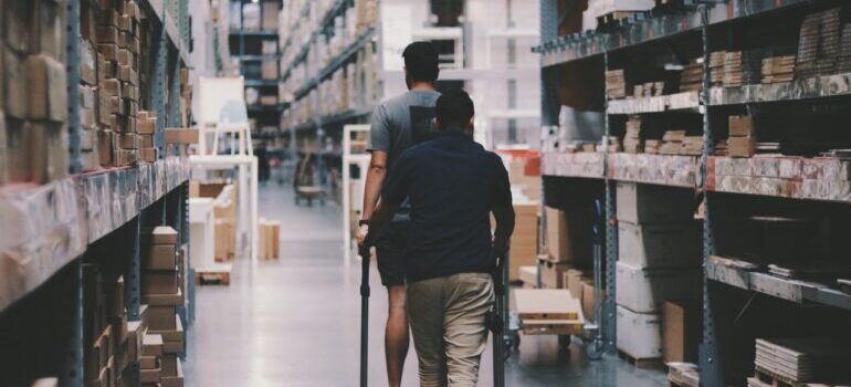 Two people looking for something in a warehouse with boxes.