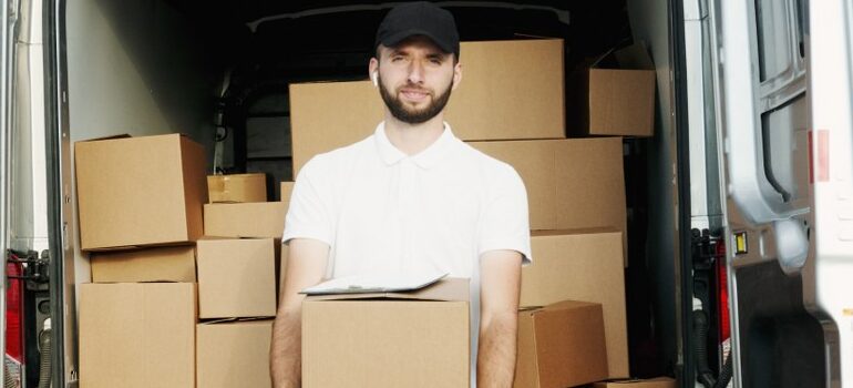 male in a black hat and white shirt holding a box