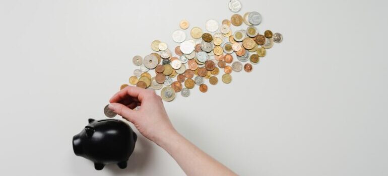 A woman putting money in a black piggy bank against a white background.