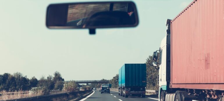 A moving truck on a highway seen from a windshield of a car.