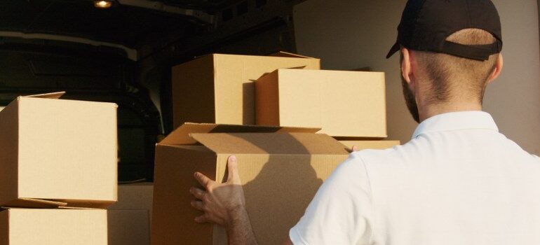 male in a white shirt and black hat loading a van