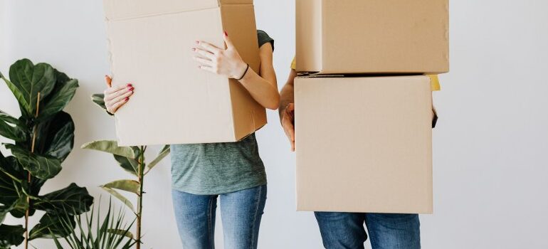 two people holding cardboard moving boxes