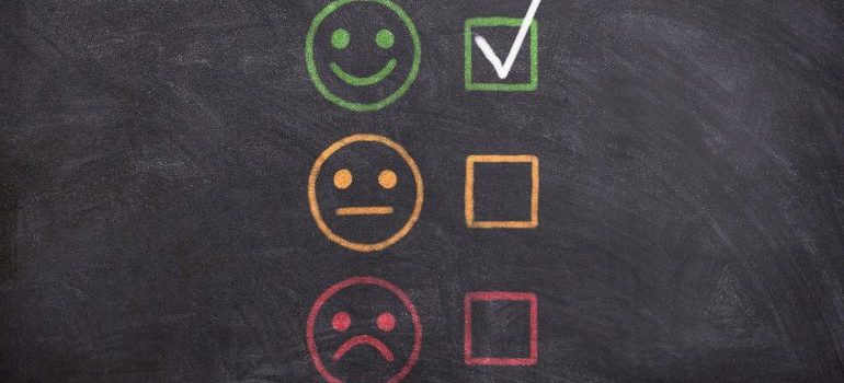 A blackboard containing three emojis depicting different emotions, and checkboxes next to them.