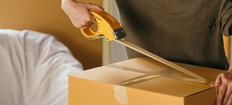 best cross country movers Great Falls applying packing tape on a cardboard box.