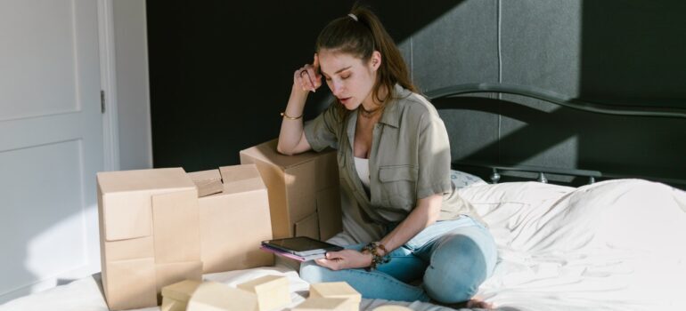 A woman sitting on the floor surrounded by packing materials.