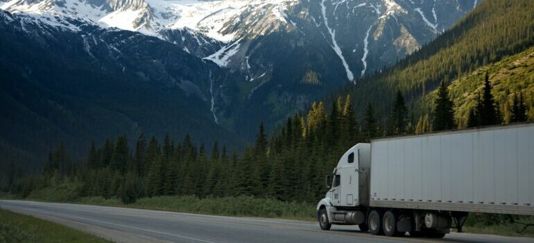 White truck on the road with mountains in the background.
