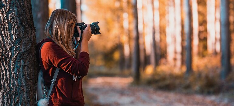 a woman taking photographs in the woods