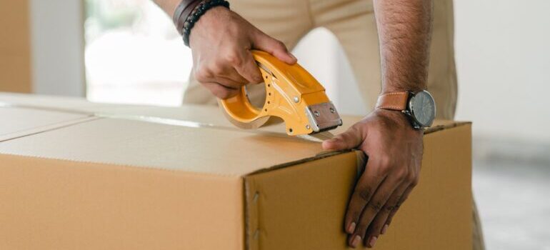 Person taping the cardboard box.