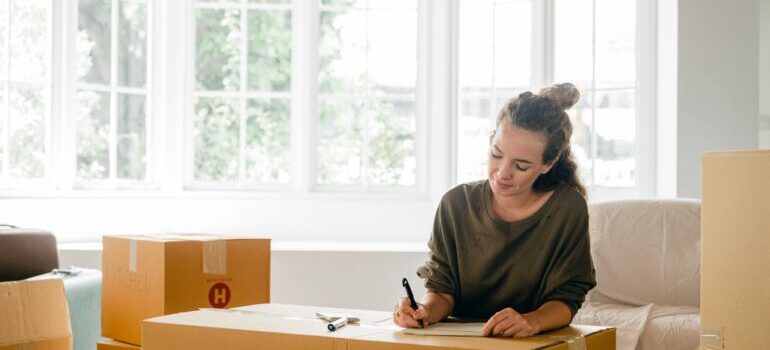 A woman writing a plan on a box