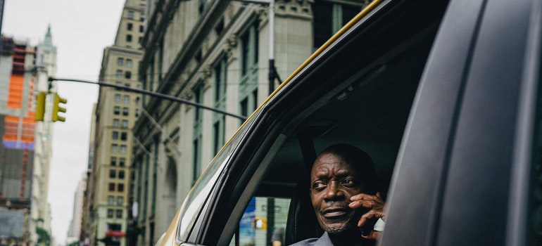 A man is riding a taxi and talking on a phone.