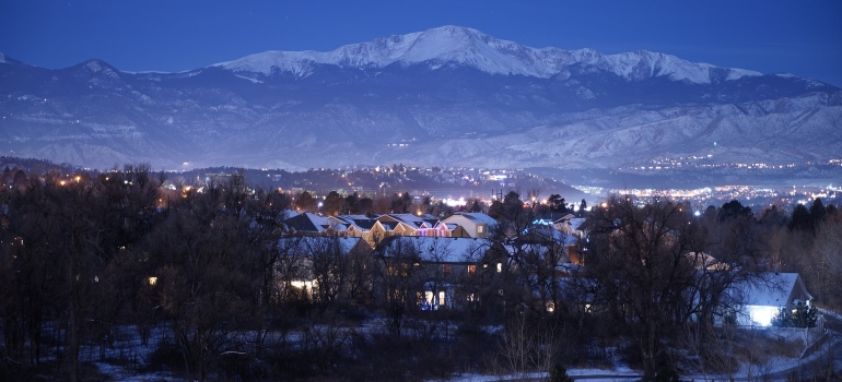 the city of Colorado Springs covered in snow with the mountain top behind it