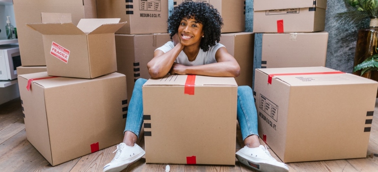 a woman smiling surrounded by moving boxes
