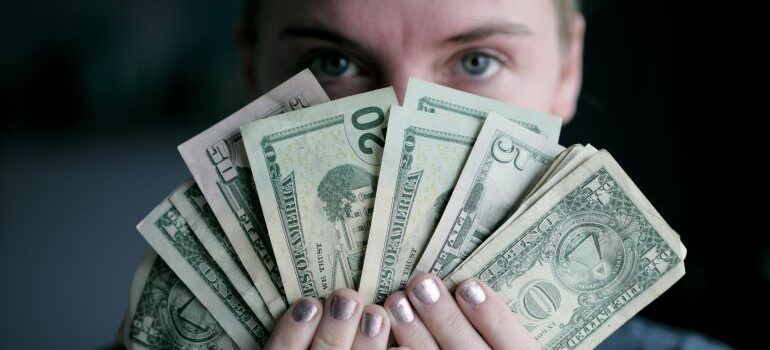 woman holding dollar bills, wondering how she can move long-distance cheap