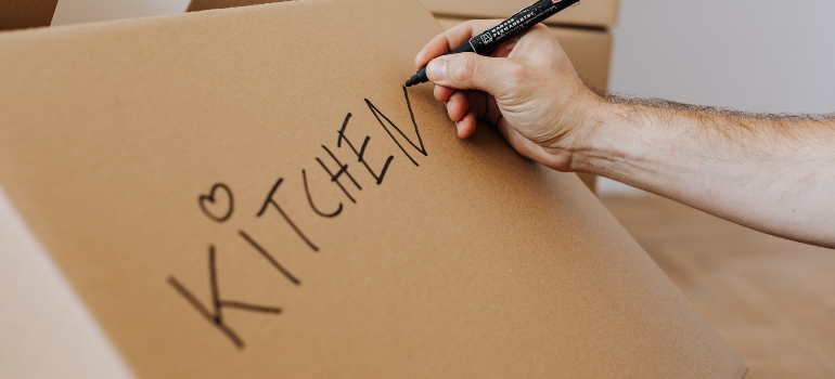 a person writing kitchen on a moving box