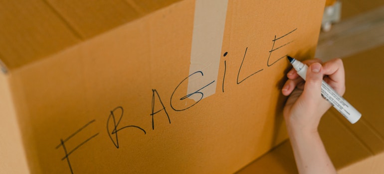 A woman writing "fragile" on the box