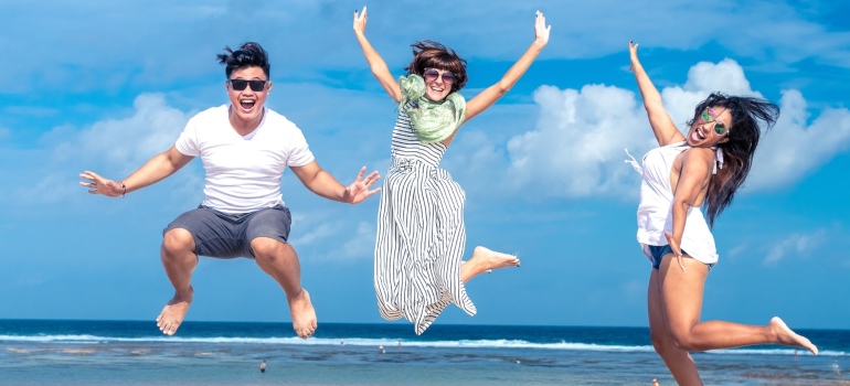 three people jumping with joy on a beach