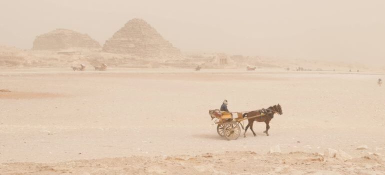 a man moving through the dessert with a horse