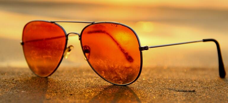Sunglasses on a beach with the sun in the background
