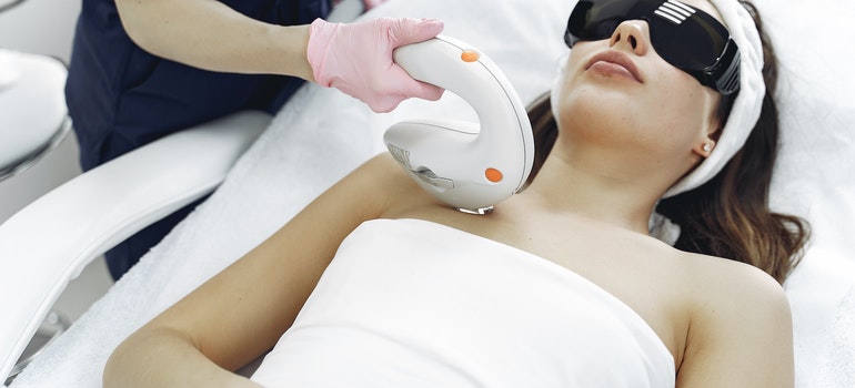 A female cosmetologist provides procedures with a laser.