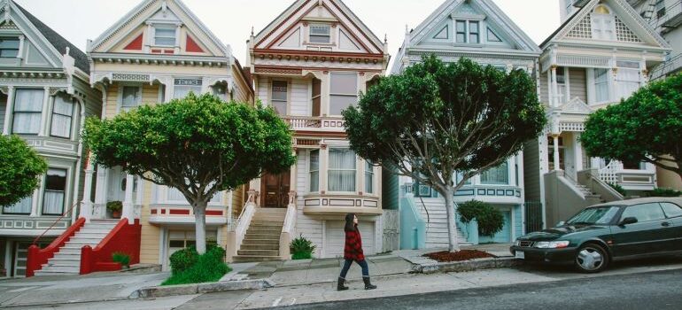 a girl walking past houses in San Francisco. 