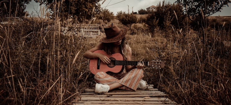 A woman playing a guitar outdoors in Texas.