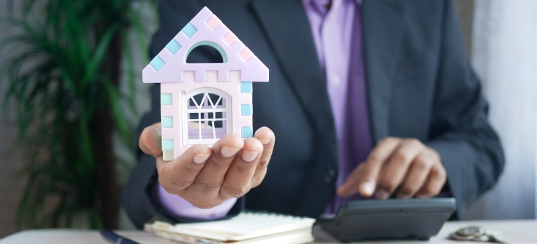 a man holding a small model of a house