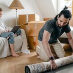 Woman with laptop and boyfriend laying carpet in flat