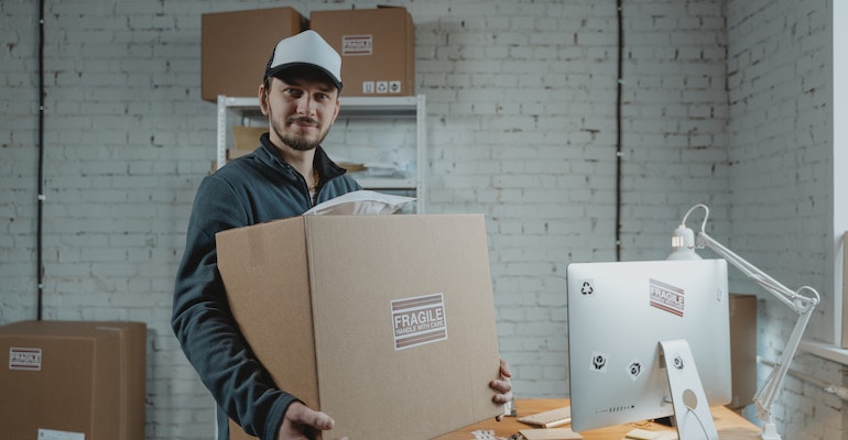 A professional mover holding a box marked fragile