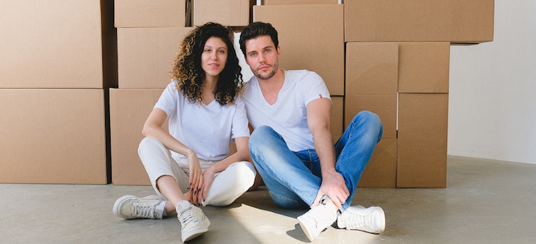 A couple with moving boxes waiting for best cross country movers El Paso
