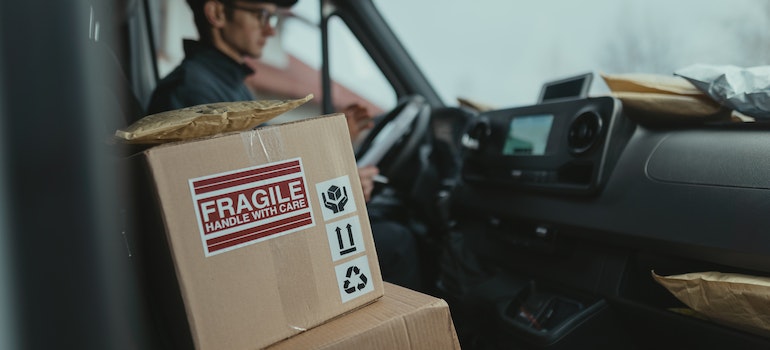 A mover in a moving truck with a box that says "fragile"